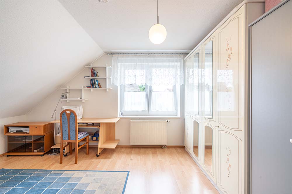 Helles Schlafzimmer mit Bett, Schreibtisch und Kleiderschrank- Ihr Immobilienmakler KRAN IMMO in Paderborn